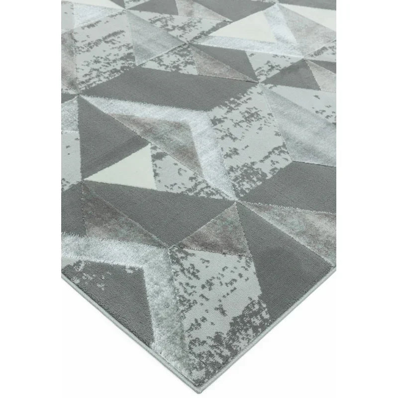 Grey geometric area rug with abstract triangle pattern, close-up of corner detail