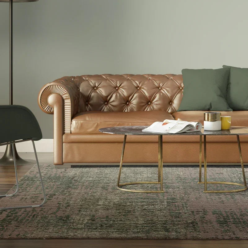 Tan leather chesterfield sofa with green cushions beside modern coffee tables in living room