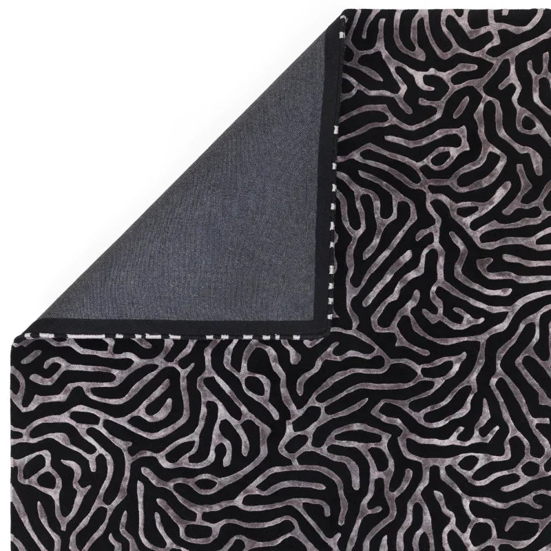 Black and silver patterned rug with geometric abstract design and hemmed edge detail