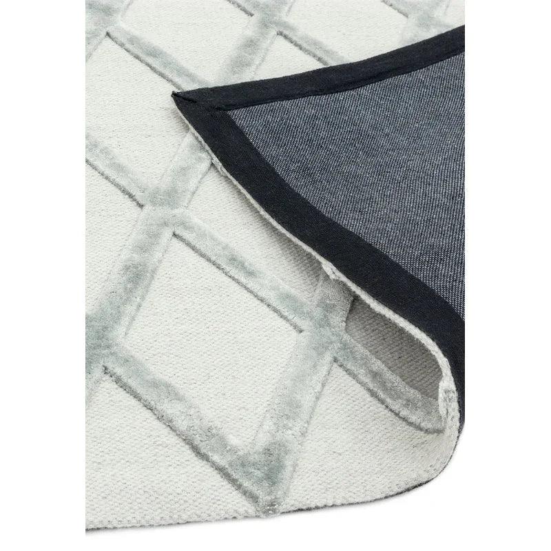 Light grey geometric rug with corner flipped to show non-slip backing