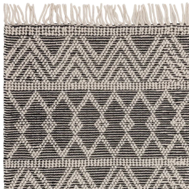 Black and cream geometric patterned rug with fringe edge, close-up of woven texture