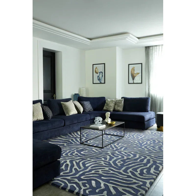 Navy blue corner sofa with scatter cushions in modern living room, patterned blue rug, coffee table