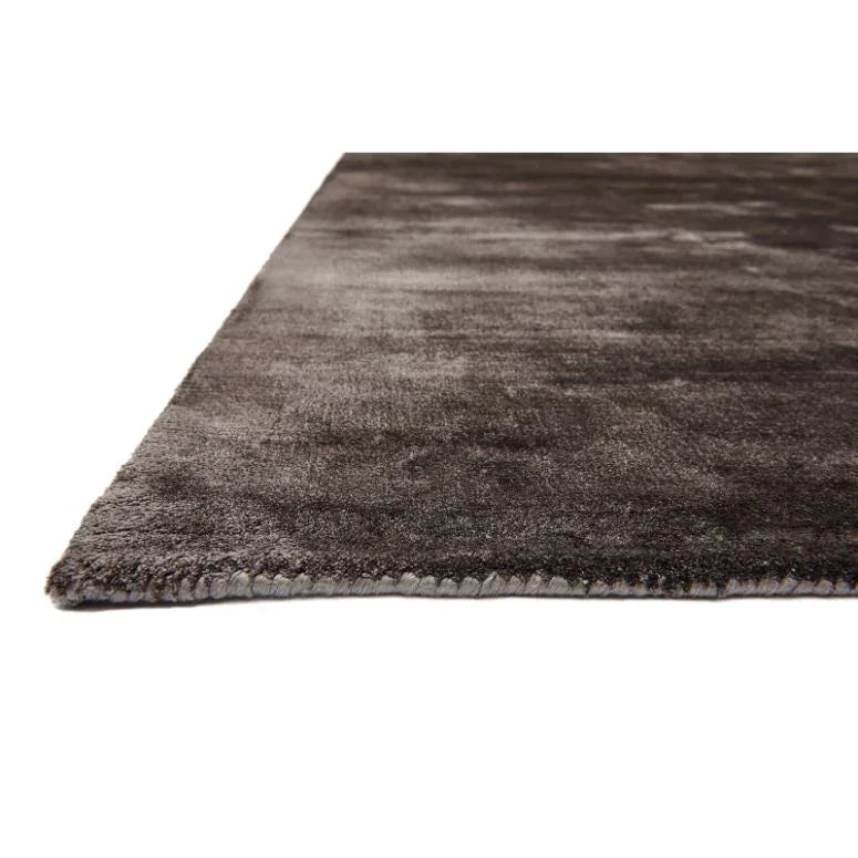 Dark grey area rug with short pile shown from a low side angle