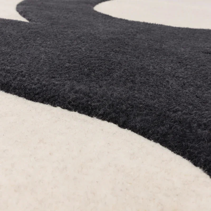 Close view of black and cream wool rug with abstract wave design