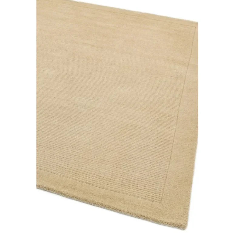 Beige wool area rug with subtle border pattern and textured finish, corner view
