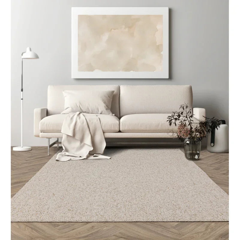 Beige fabric sofa with throw and cushion, neutral rug on herringbone floor, modern living room