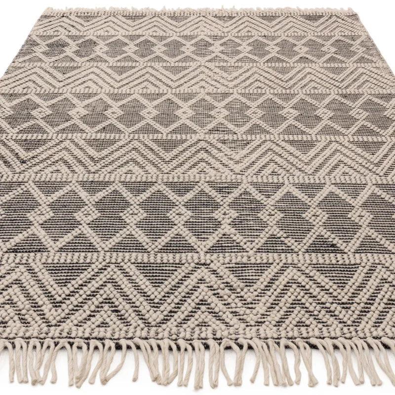 Patterned area rug with cream geometric design and fringed edges