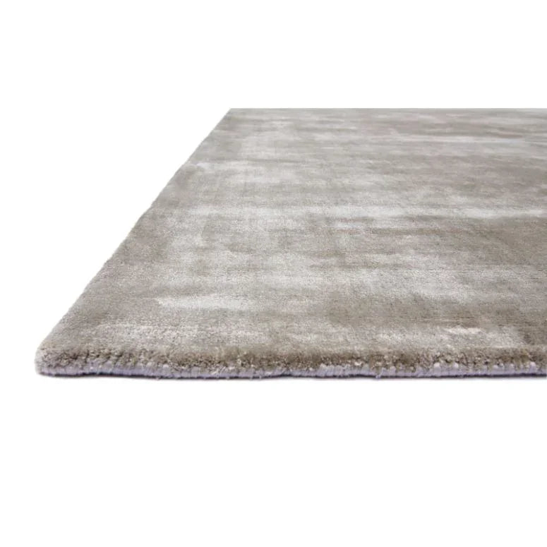 Close side view of a beige area rug with plush pile and subtle sheen