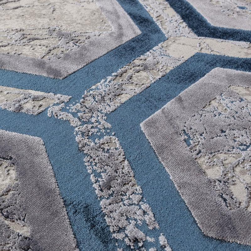 Close up of geometric patterned rug in blue, grey and beige with textured pile