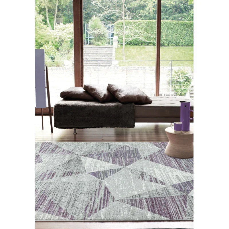 Modern geometric area rug in grey and purple tones on living room wooden floor