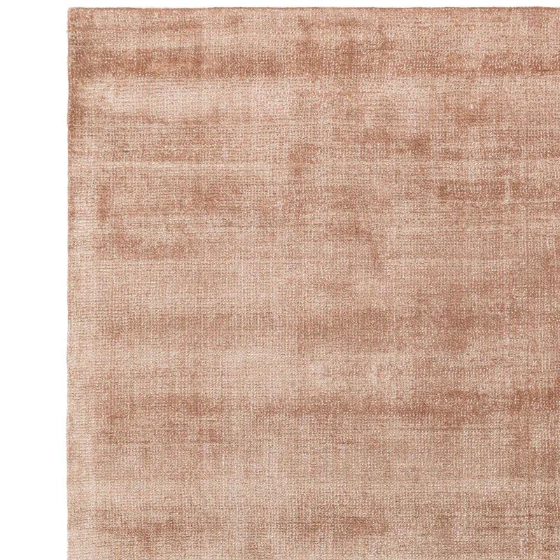 Blush pink area rug with soft textured finish and subtle pattern, corner detail shown