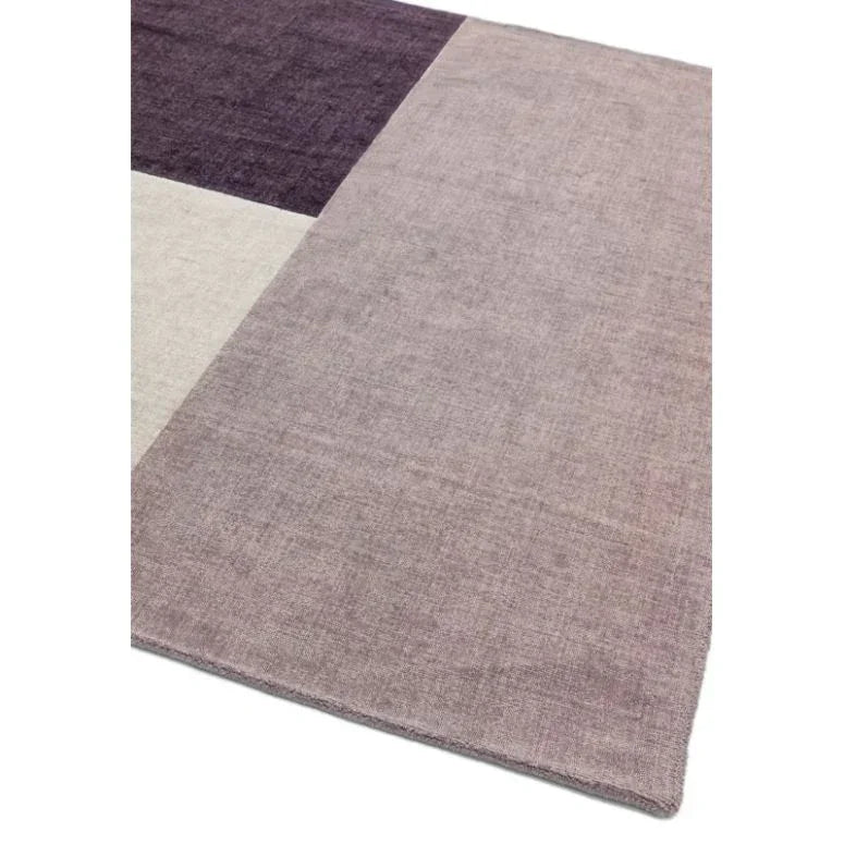 Modern area rug with purple, lavender, and beige color blocks, close-up corner view
