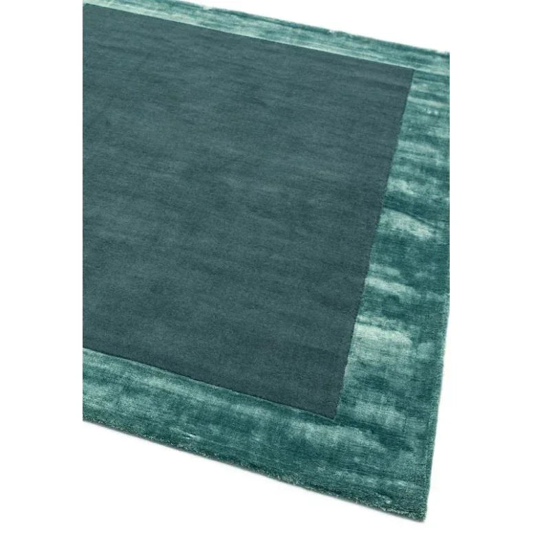 Teal rectangular area rug with solid center and textured border, corner angled view