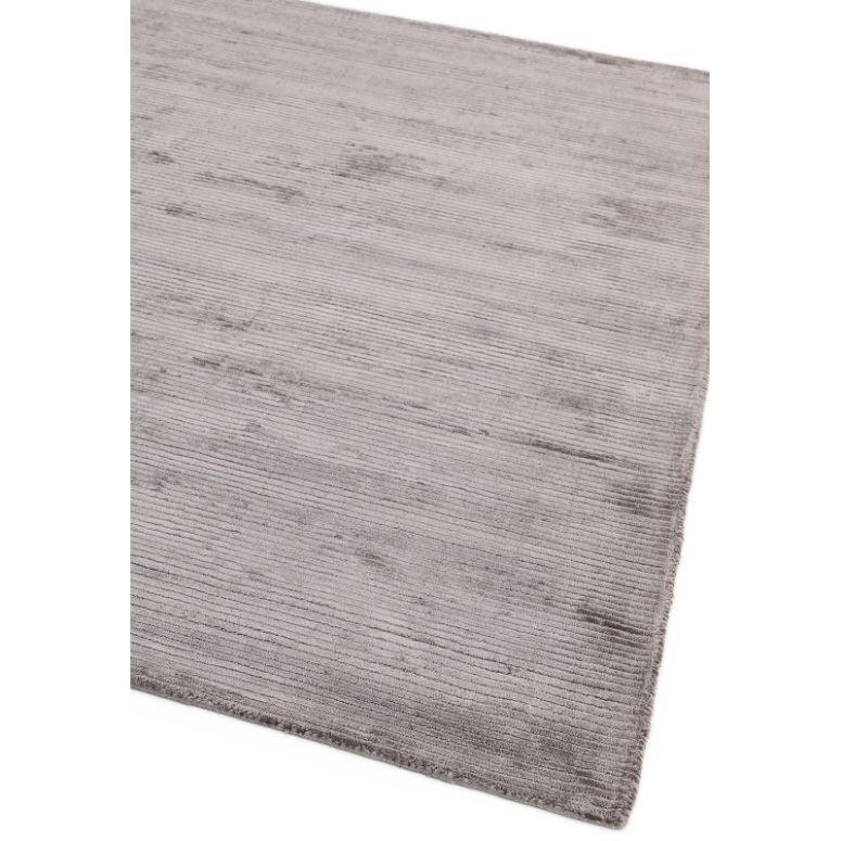 Light grey area rug with subtle textured lines, close-up of corner on white background