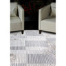 Modern striped area rug in grey and cream tones placed between two beige armchairs