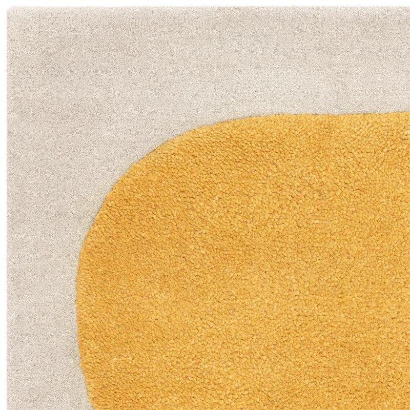 Close up of modern area rug with yellow abstract shape on cream background