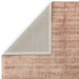 Blush pink area rug with textured surface and corner folded to show backing