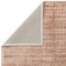 Blush pink area rug with textured surface and corner folded to show backing
