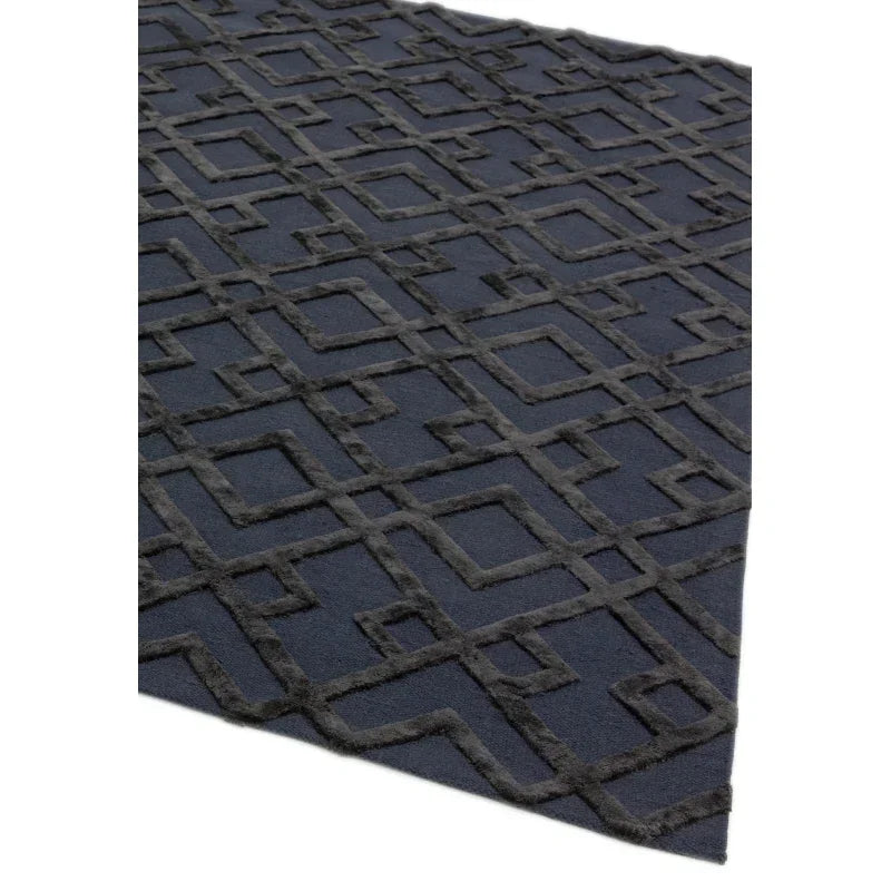 Dark geometric pattern rug with raised textured squares and rectangles, angled corner view