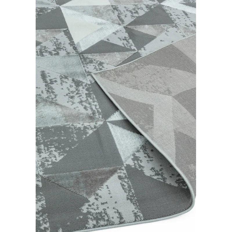 Grey geometric patterned rug with folded corner showing back texture
