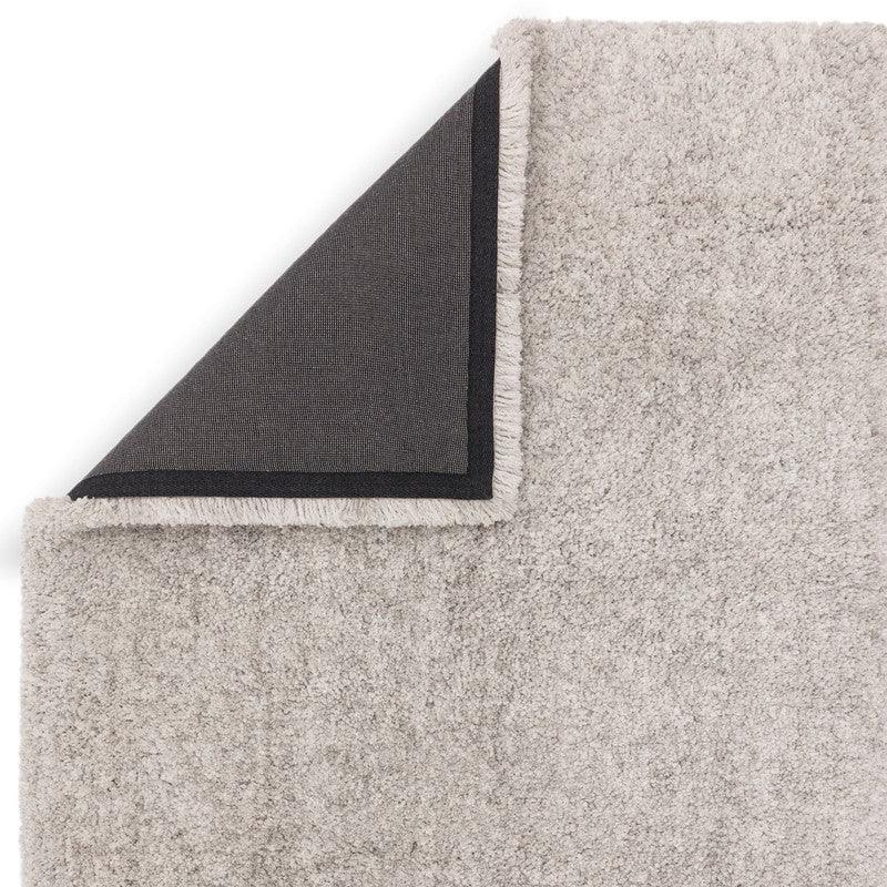 Light grey shaggy rug corner folded to show black non-slip backing