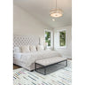 White upholstered bed with tufted headboard and bench in modern bedroom with windows