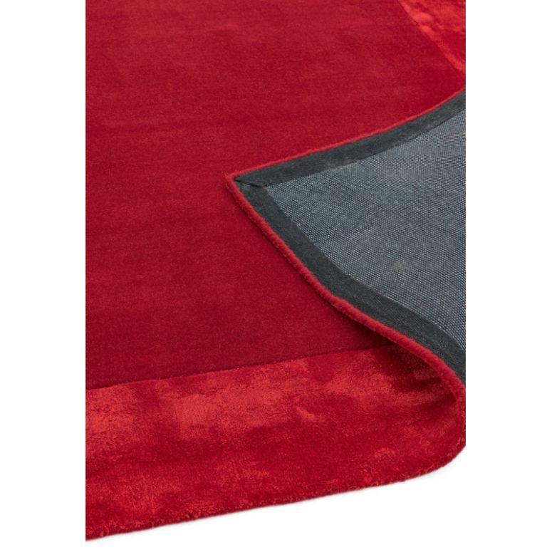 Red area rug with visible corner folded to show backing detail