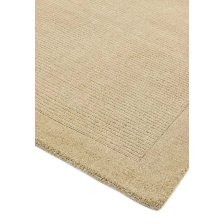 Beige area rug with textured border and subtle striped design, close-up corner view
