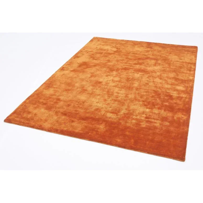 Rectangular orange velvet rug with soft texture on white background