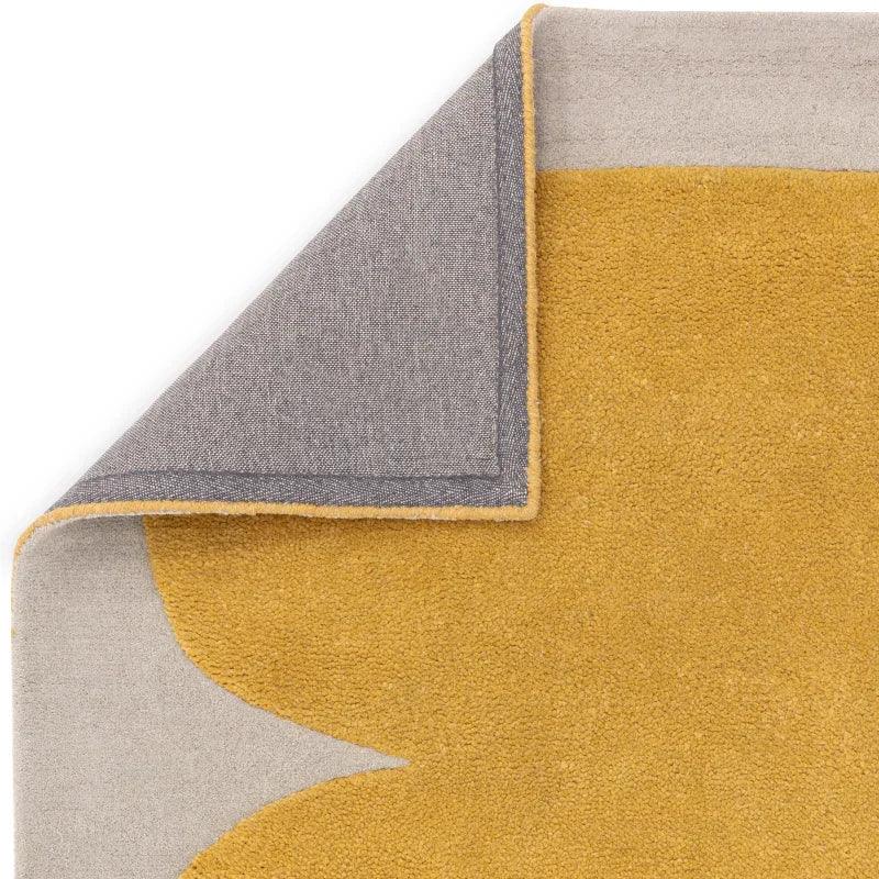Yellow and beige area rug corner with visible backing and modern abstract design