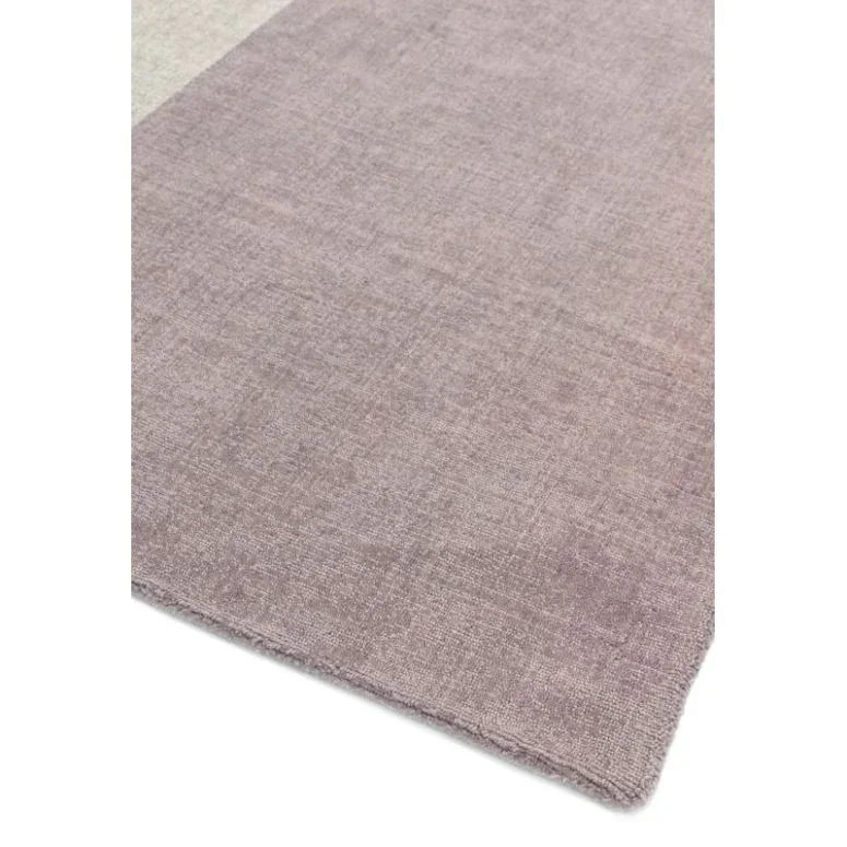 Closeup of a light mauve area rug with soft textured fabric and finished edge