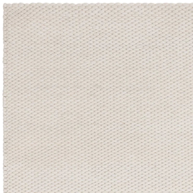 Closeup of cream wool rug with textured weave and straight edge