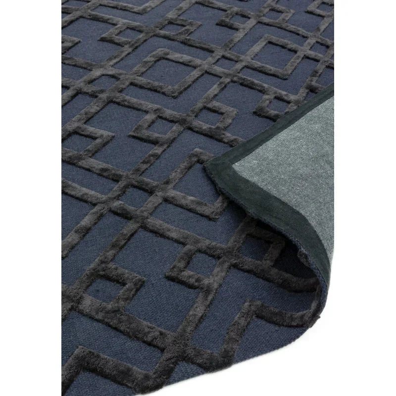 Navy blue geometric patterned rug with raised texture and folded corner detail