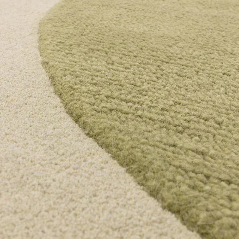 Close up of green and beige wool rug texture with curved edge design