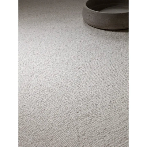 Textured cream wool rug with loop pile detail beside round stone tray