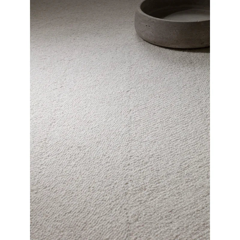 Textured cream wool rug with loop pile detail beside round stone tray