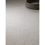 Textured cream wool rug with loop pile detail beside round stone tray