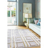 Modern geometric area rug with gold accents in blue living room with sofa and mirror