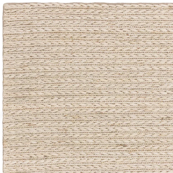 Close-up of cream woven wool rug corner showing textured braided pattern