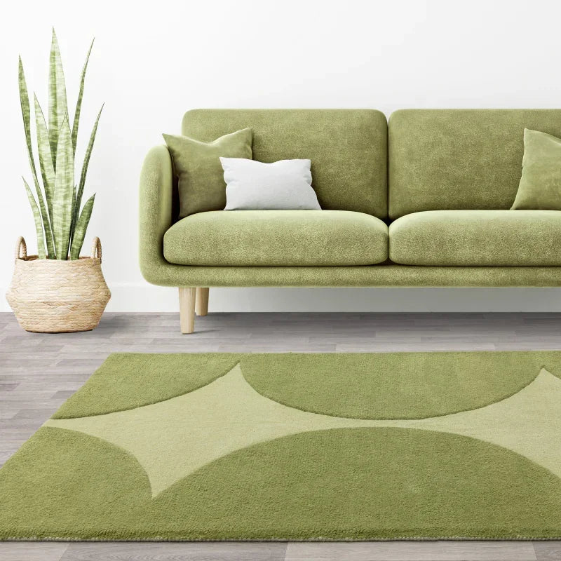 Green fabric sofa with wooden legs, geometric rug, and indoor plant in wicker basket in living room