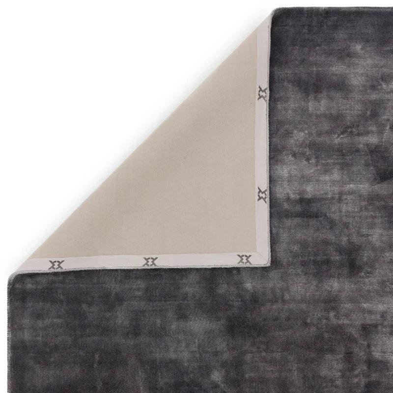 Charcoal velvet rug corner flipped to show beige backing and stitched edge detail