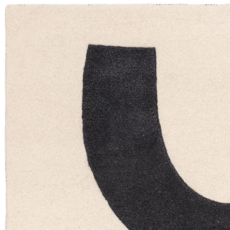 Modern area rug with thick black curved design on cream background, close-up texture view