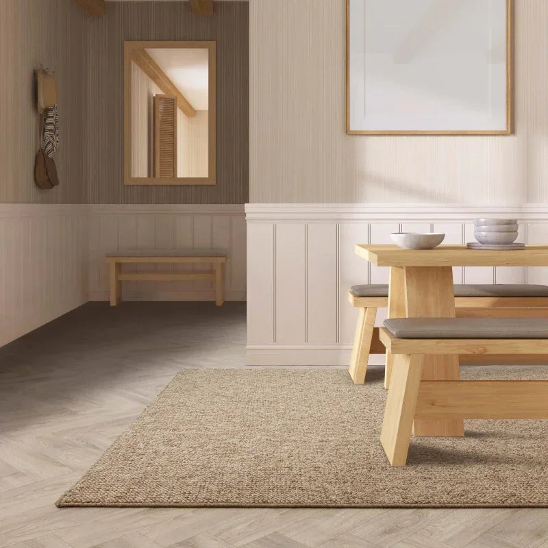Light wood dining table with matching bench and neutral cushions in a modern dining room