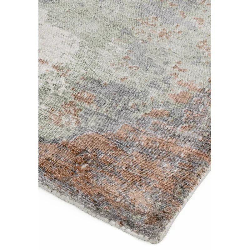 Abstract pattern area rug with muted green, grey and brown tones, corner close-up view