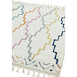 White geometric area rug with colorful zigzag patterns and tassel fringe detail