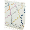 White geometric area rug with colorful zigzag patterns and tassel fringe detail