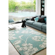 Large floral patterned rug in modern living room with teal sofa and decorative cushions
