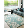 Large floral patterned rug in modern living room with teal sofa and decorative cushions