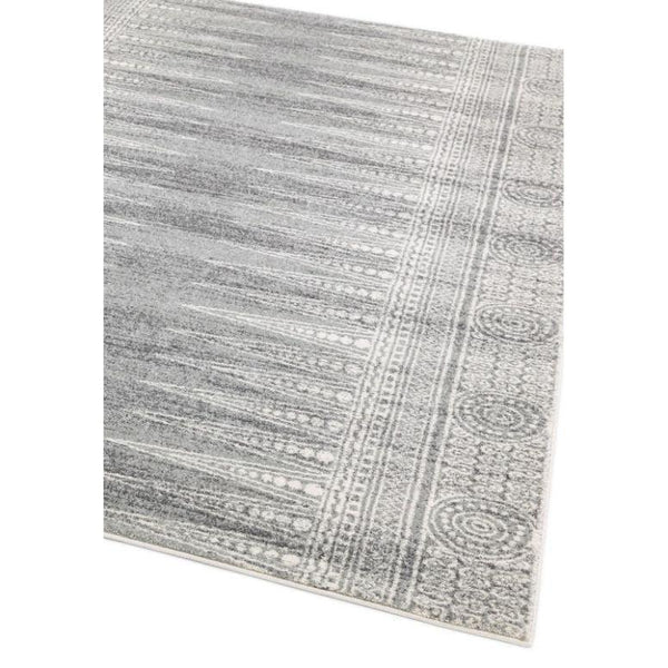 Grey patterned area rug with textured border and circular detailing, angled corner view