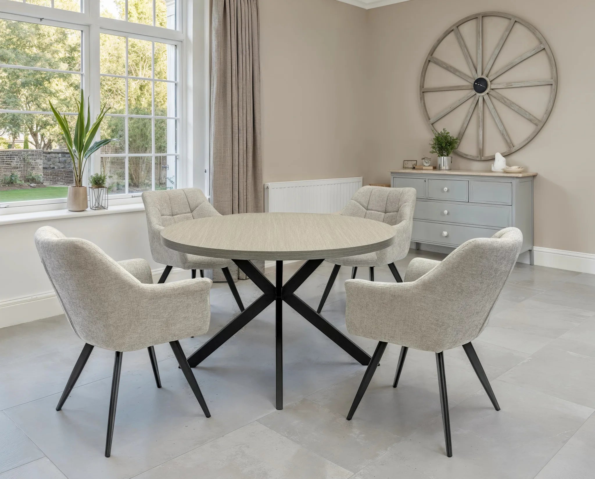 Dining room with round table and chairs near a large window.